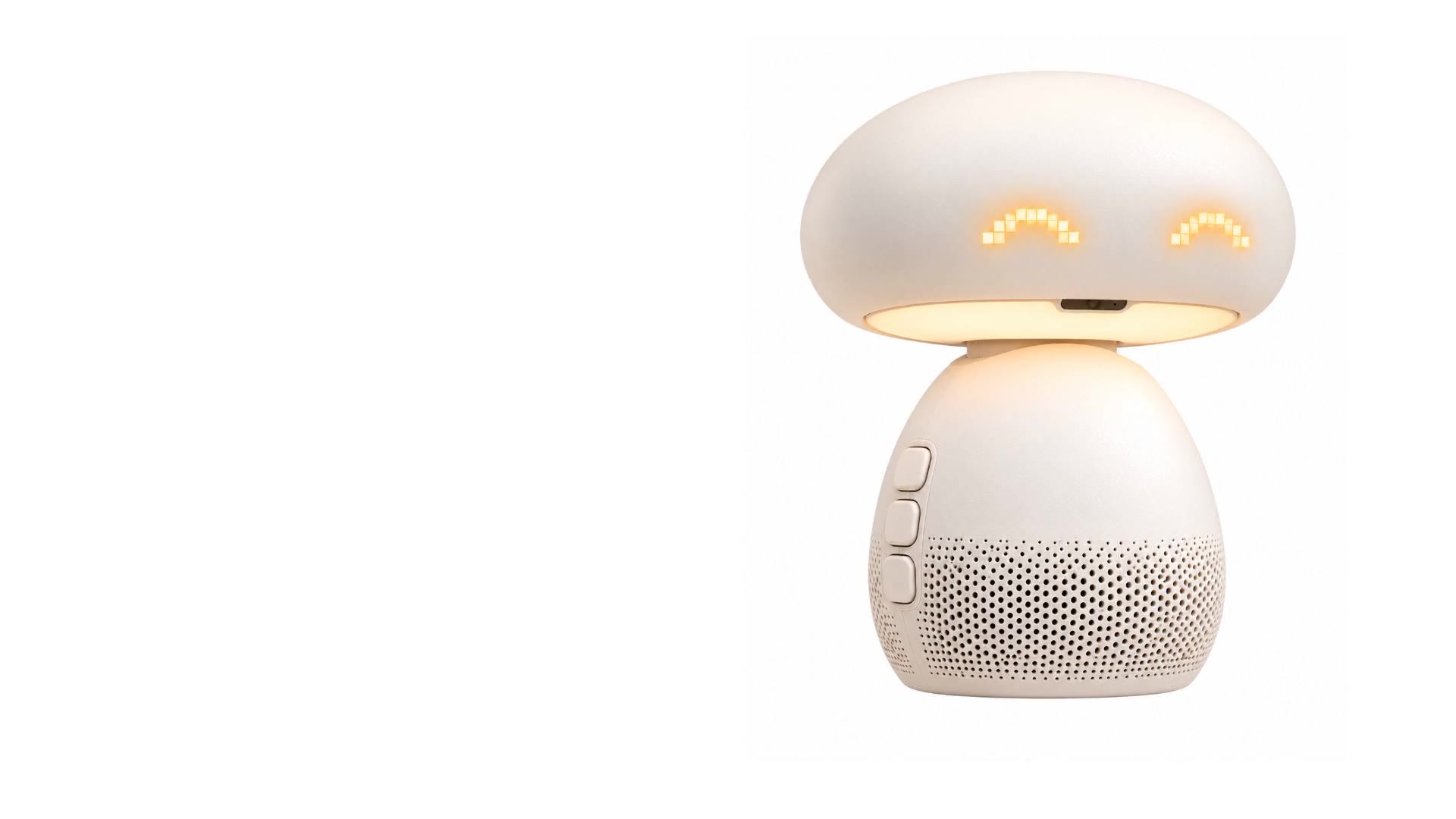 Still from the film: the device on white, lamp on, warm pixel eyes